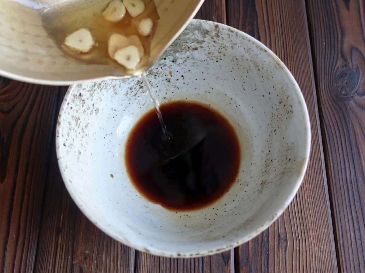 Vertiendo el aceite de ajo caliente en el cuenco de la salsa de soja.