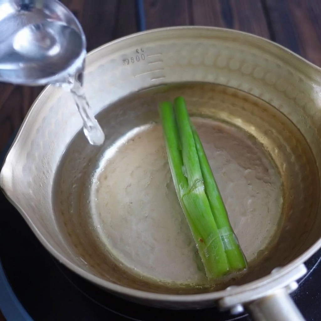 Añadiendo sake y mirin a la olla con agua y cebolletas.