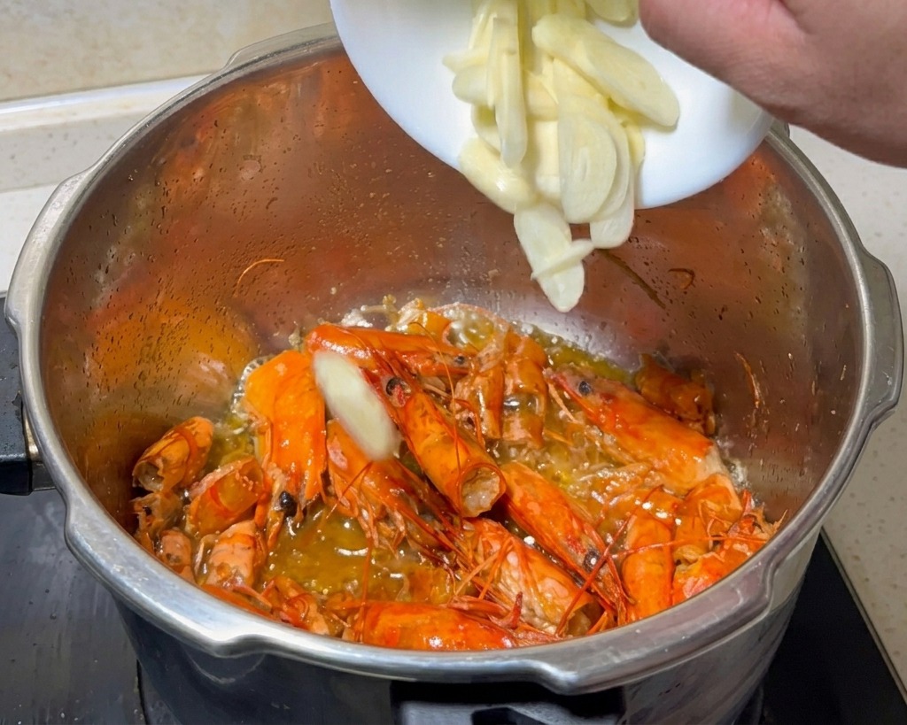 Ajo laminado añadiéndose a la olla con las cáscaras de gamba fritas.