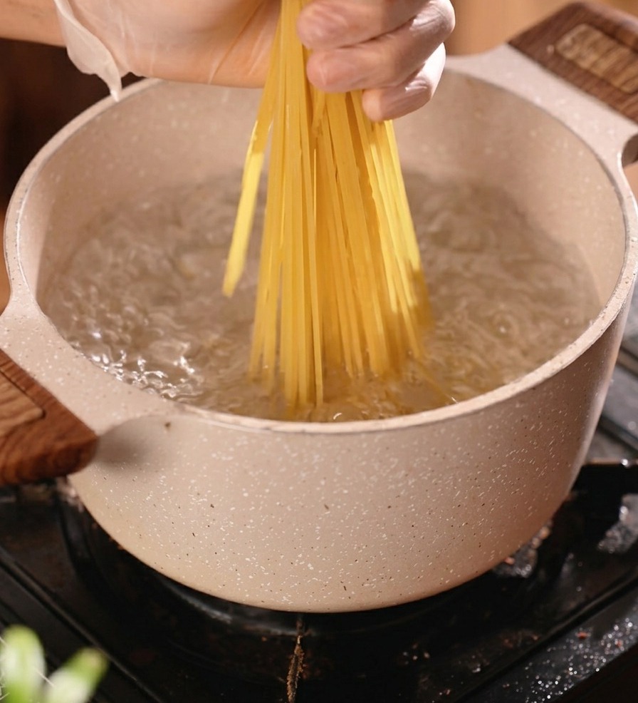 Espaguetis secos introduciéndose en una olla de agua hirviendo.
