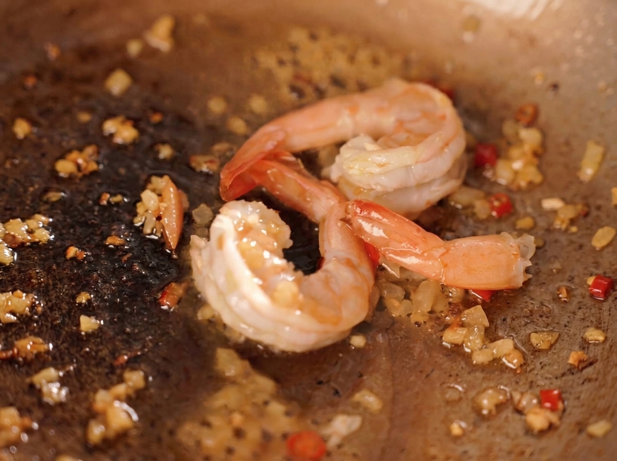 Gambas salteándose con trozos de yema de huevo salada y polvo de yema dorado.
