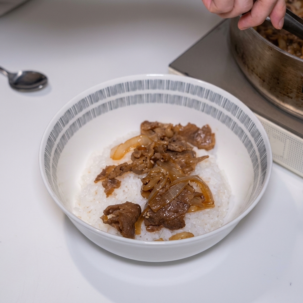 Unas pinzas colocando ternera sabrosa cocinada a fuego lento y cebollas blandas sobre una cama de arroz blanco al vapor en un tazón.