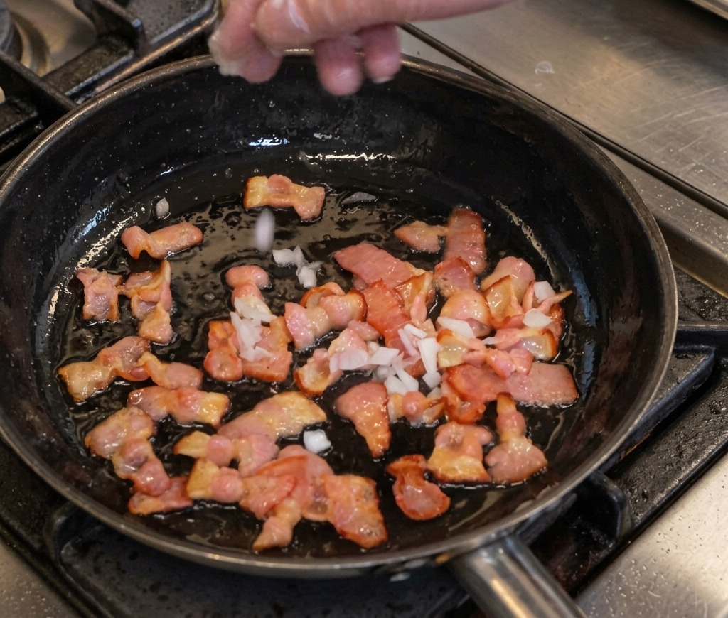 Añadiendo cebolla picada a la sartén con el tocino dorado.