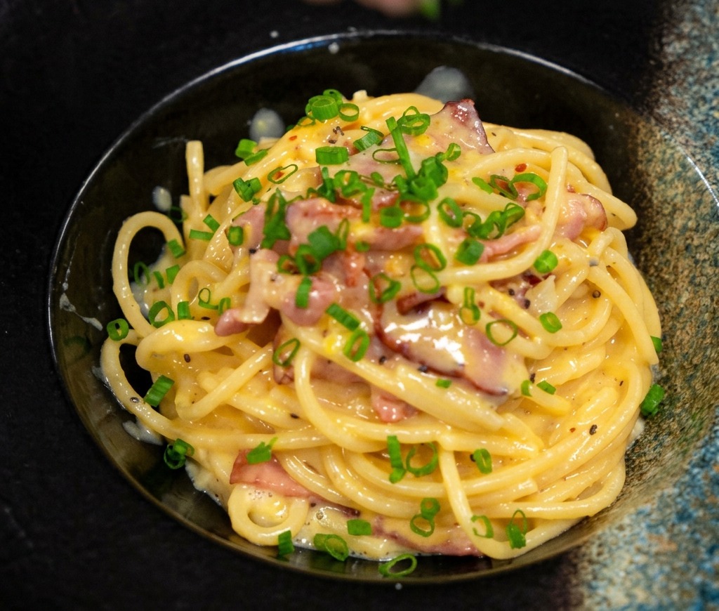 Espolvoreando cebollín fresco picado sobre un plato de pasta cremosa bien presentado.