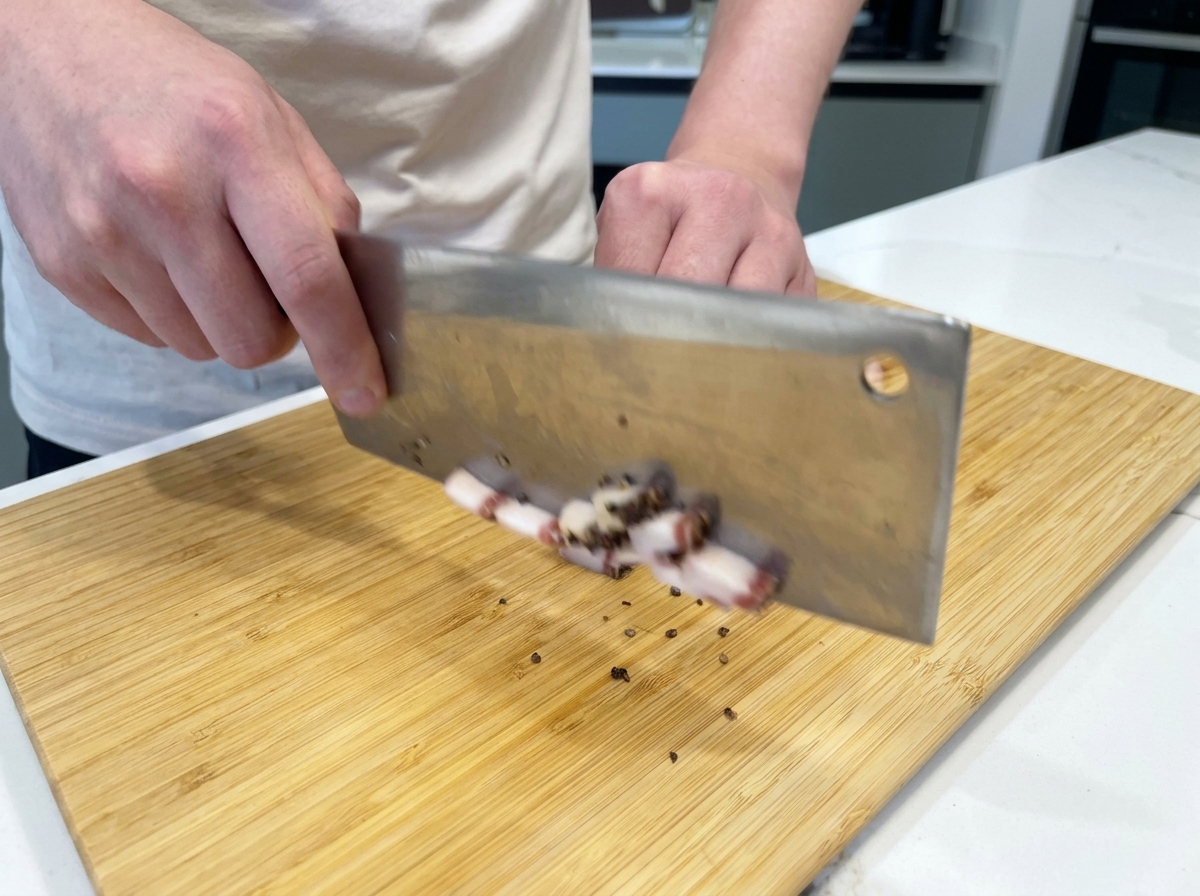 Un chef cortando tiras de guanciale curado en dados pequeños sobre una tabla de bambú.