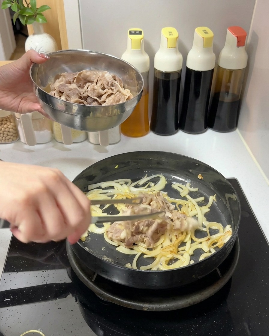 Añadiendo un tazón de láminas de ternera cocinada en una sartén que contiene cebollas salteadas.