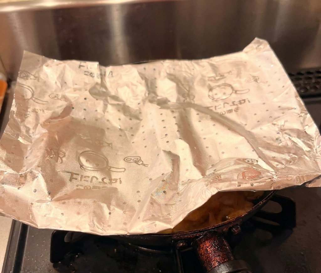 El acompañamiento terminado de pollo y huevo deslizándose con cuidado desde una sartén hacia un cuenco de arroz blanco.