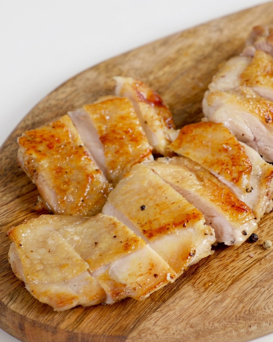 Contramuslo de pollo frito y crujiente cortado en varios trozos uniformes sobre una tabla de madera.
