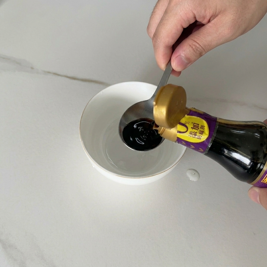 Salsa de soja oscura vertiéndose desde una botella en un pequeño tazón de cerámica blanca que contiene otros ingredientes líquidos.