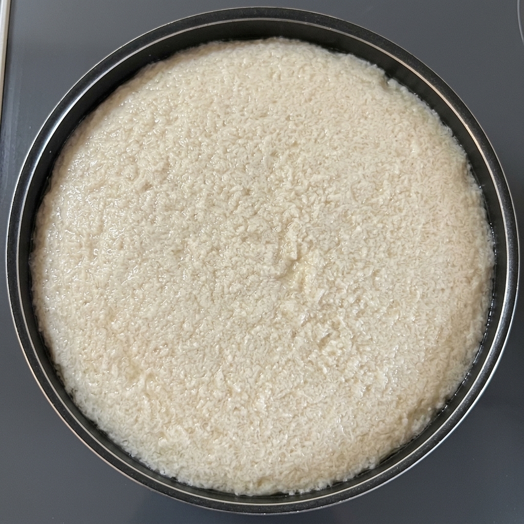 Una hoja circular de papel absorbente de aceite flotando sobre la superficie del agua en una olla negra para retirar la espuma de la cocción.