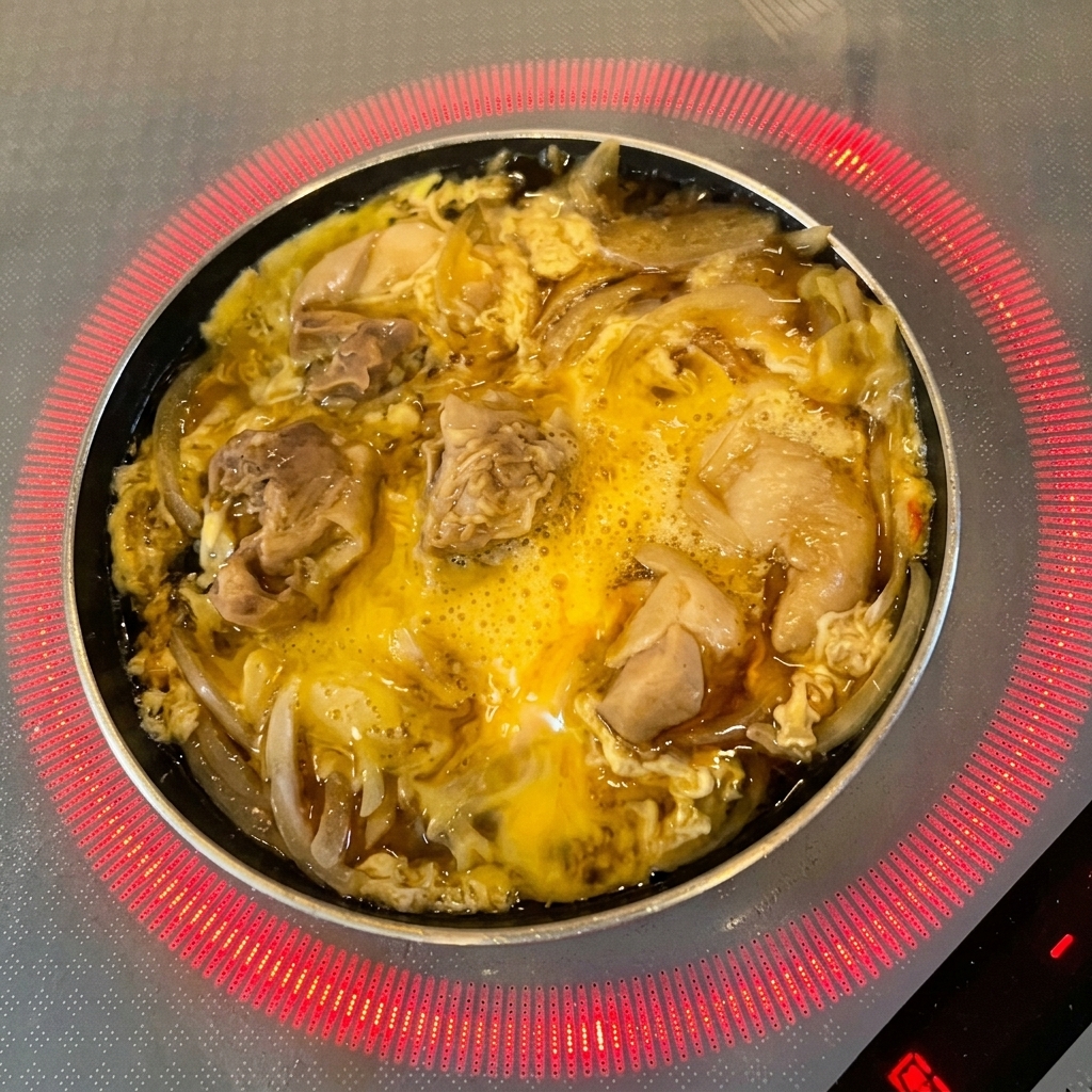 Hojas verdes frescas de mitsuba esparciéndose sobre el huevo parcialmente cocido y el pollo.