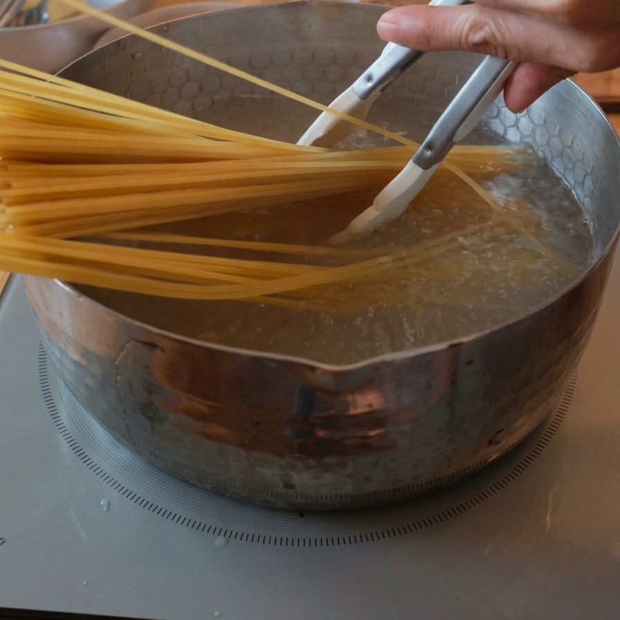Un manojo de espaguetis secos siendo sumergidos en una olla de agua hirviendo con burbujas.