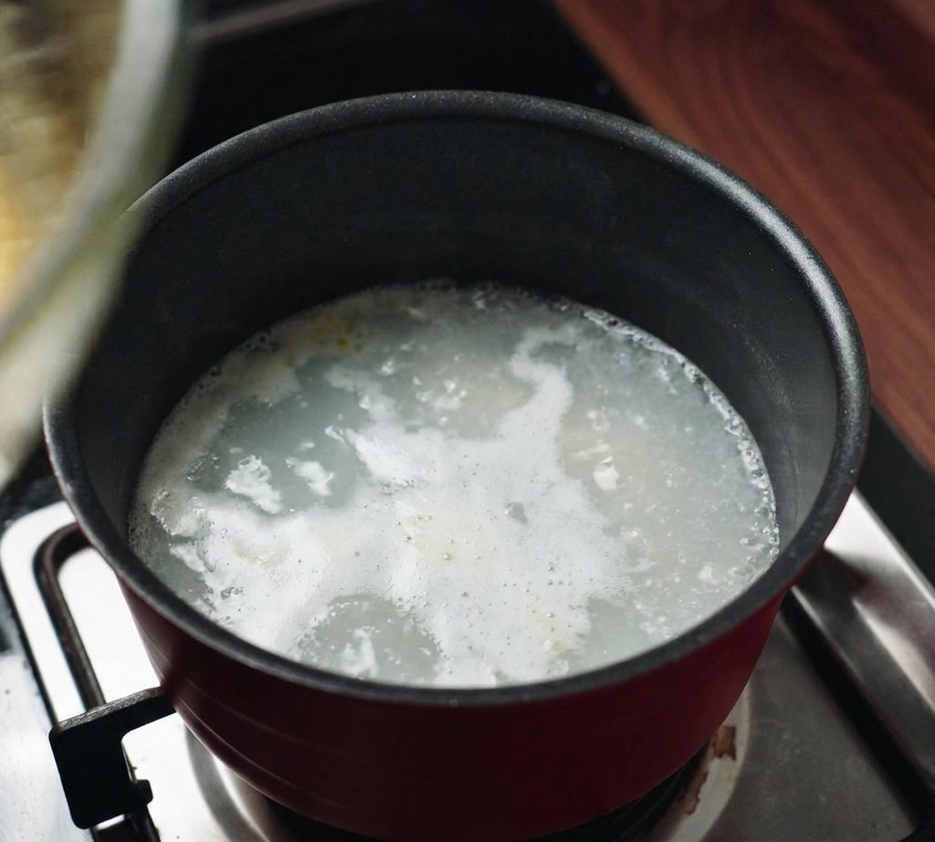 Un bol de cristal colocado sobre una olla con agua humeante para crear un baño maría en la cocina.