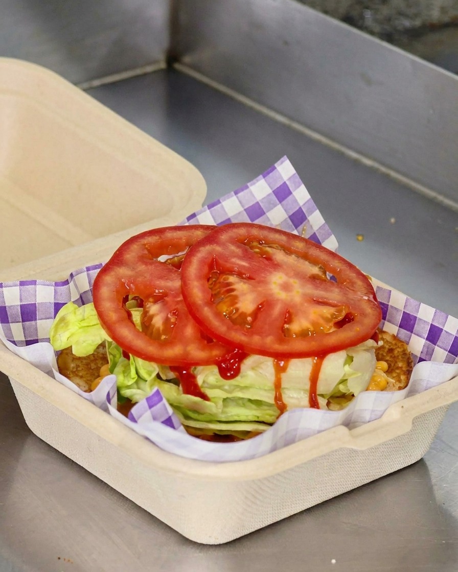 Dos rodajas de tomate rojo fresco colocadas sobre la lechuga en un contenedor de comida.
