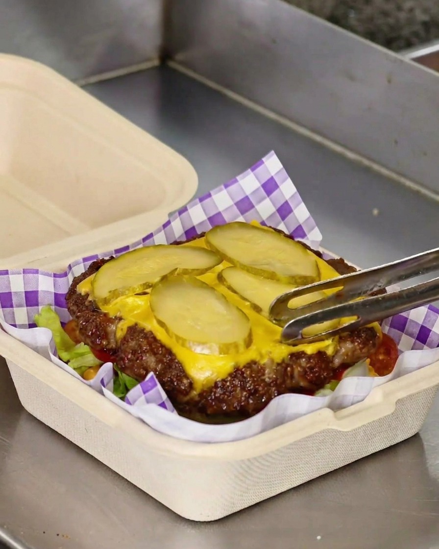 Transfiriendo la carne con queso y pepinillos sobre la cama de lechuga y tomate.