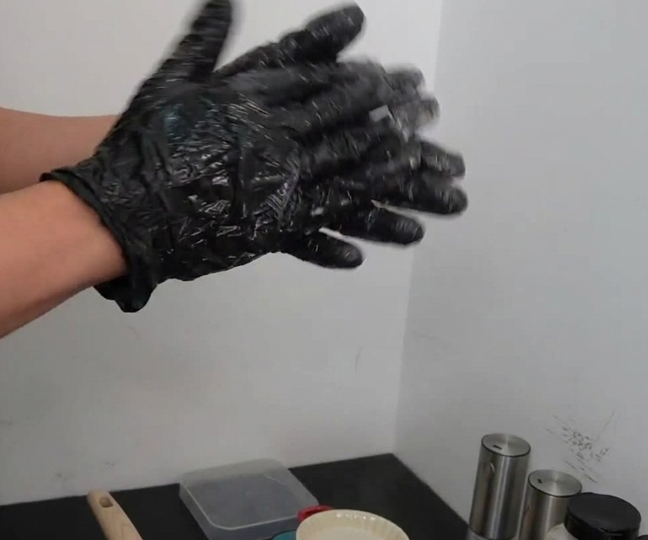 Dos manos con guantes lanzando y golpeando con firmeza una bola de carne sazonada de una mano a otra.