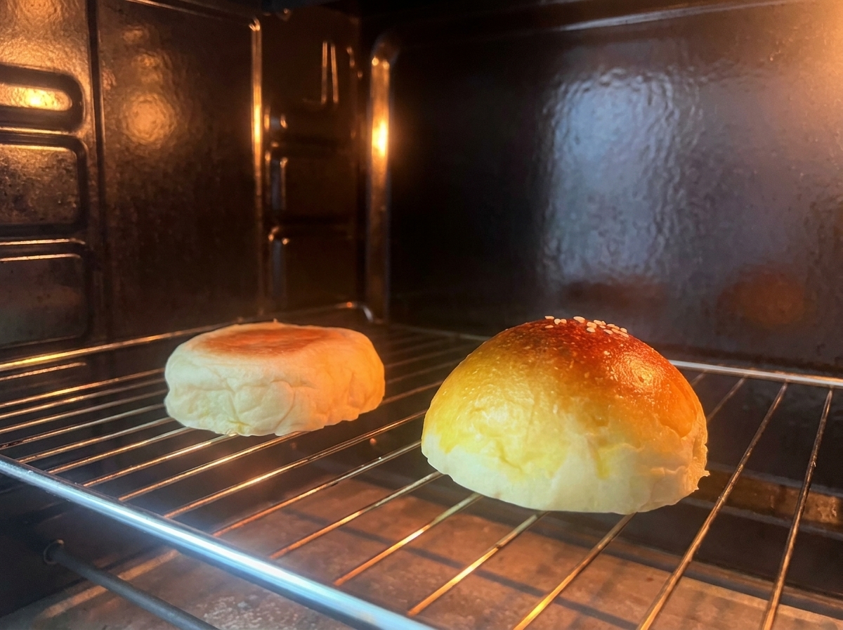 Dos mitades de un pan de hamburguesa tostándose en una rejilla dentro de un horno.