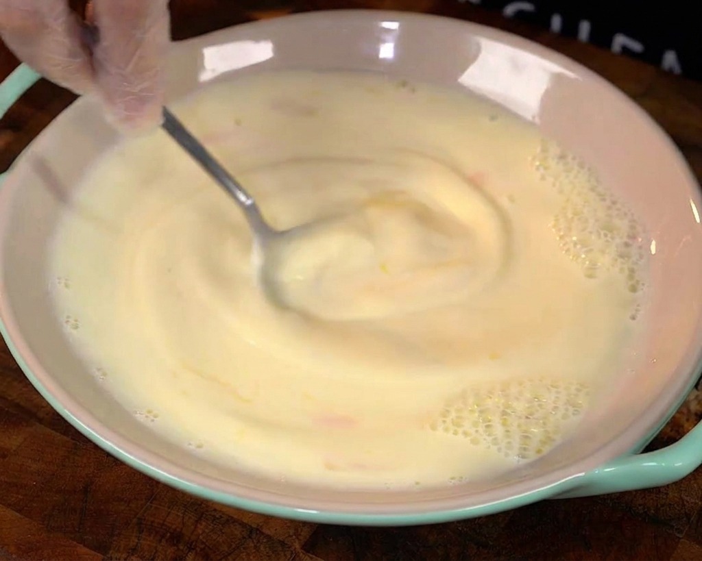 Una cuchara batiendo la mezcla de huevo y leche en un bol.