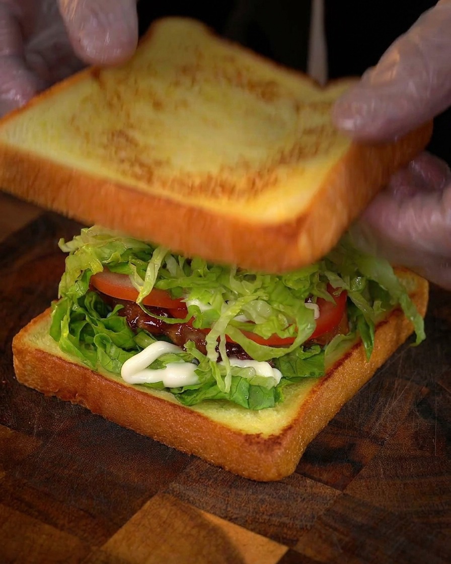 Colocando la segunda rebanada de pan dorado sobre el sándwich montado.