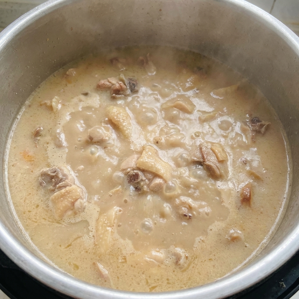 Una olla con caldo tonkotsu hirviendo con fuerza, espeso, opaco y de color blanco lechoso.