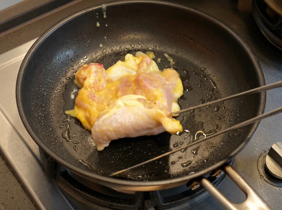 Contramuslo de pollo marinando en una sartén caliente con aceite.