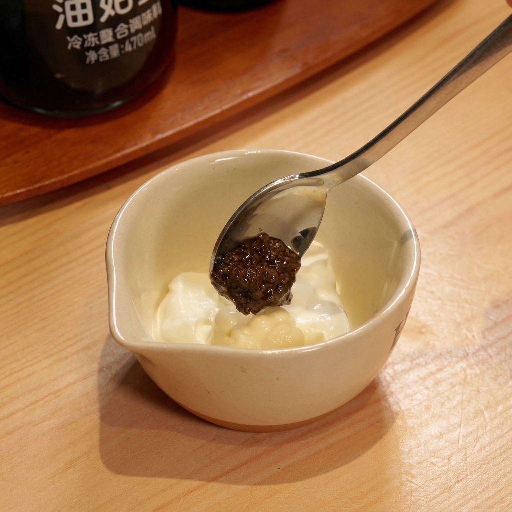 Añadiendo pasta de trufa negra a la crema de yogur y mayonesa.