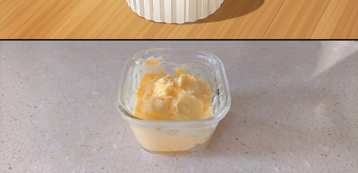 Un pequeño recipiente de cristal con una mezcla de mantequilla y mostaza amarilla.