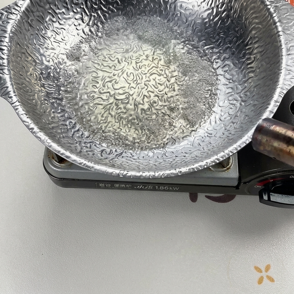 Líquido burbujeando vigorosamente en una olla plateada mientras se calienta y se enciende con un soplete para eliminar el contenido de alcohol.