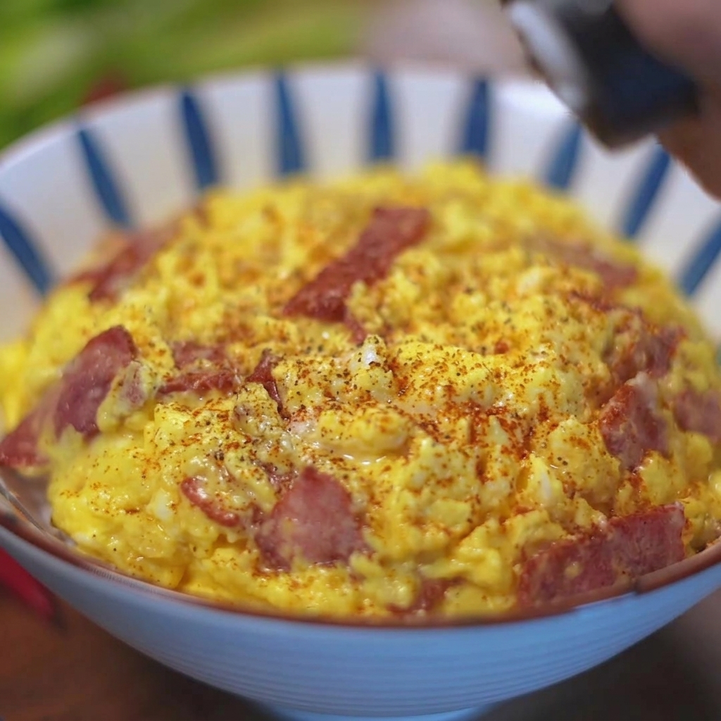 Pimienta negra fresca moliéndose sobre un tazón de huevos revueltos y tocino en una cama de arroz.