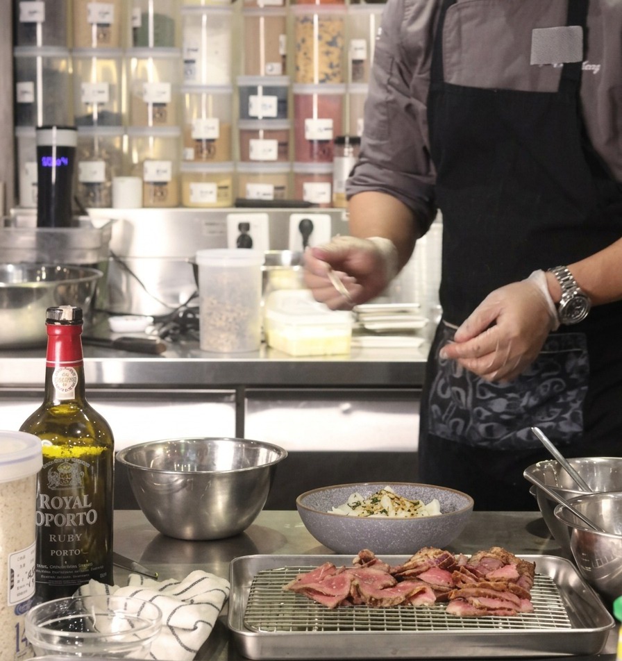 Un chef añadiendo una porción de cebollas caramelizadas doradas en el centro de un bol de arroz preparado.