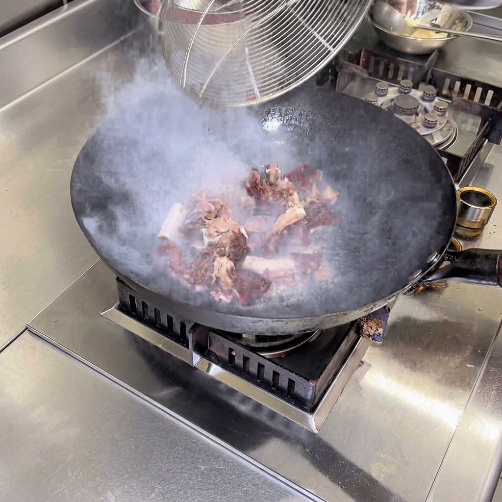 Costillas de cerdo curadas saltéandose a fuego vivo en un wok caliente con aceite de camelia.