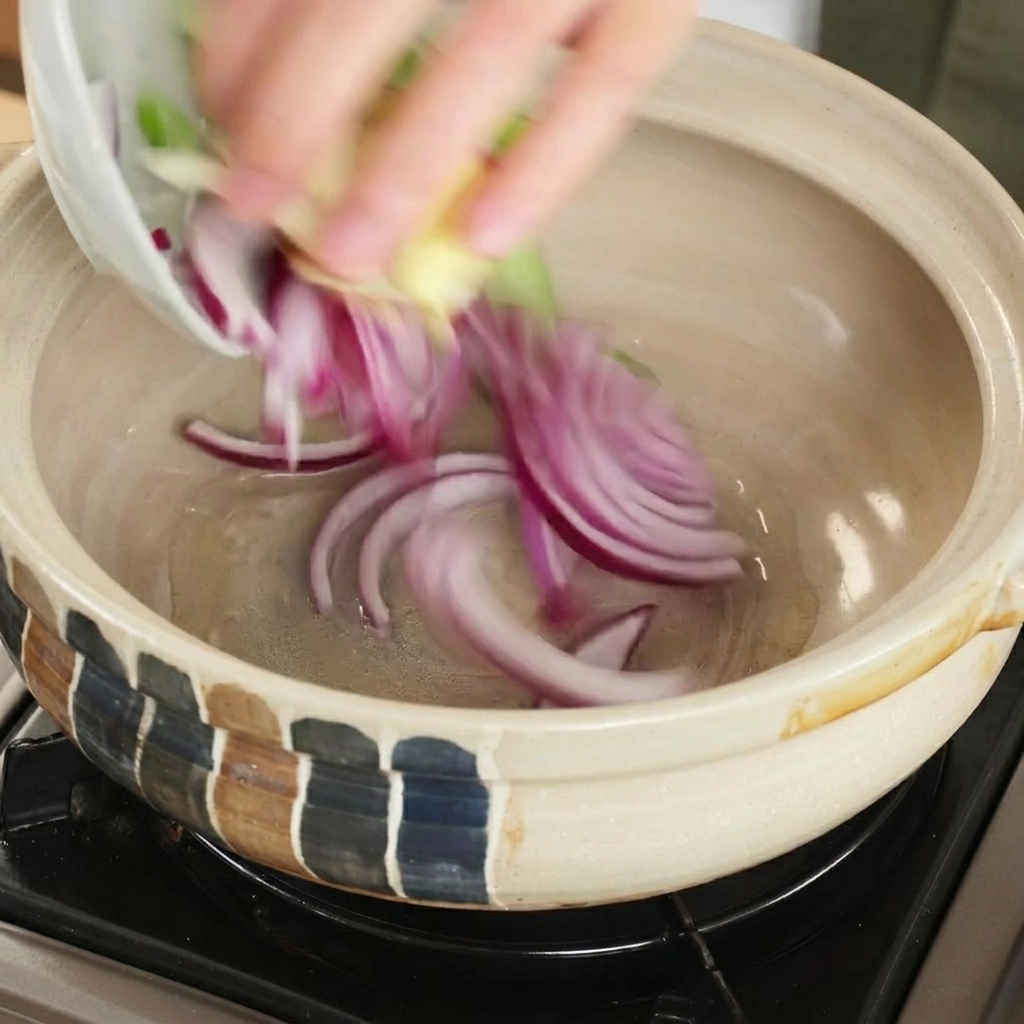 Cebolla roja y aromáticos cocinándose en una cazuela.