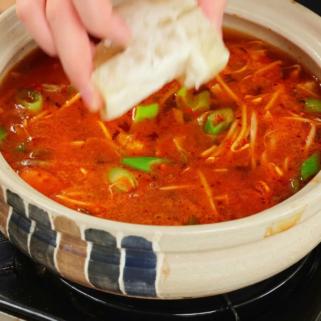 Cubo de caldo cayendo en la sopa roja.