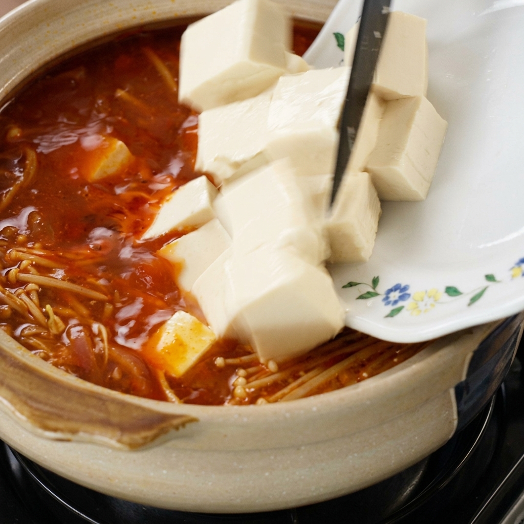 Cubo de tofu deslizándose en la sopa hirviendo.