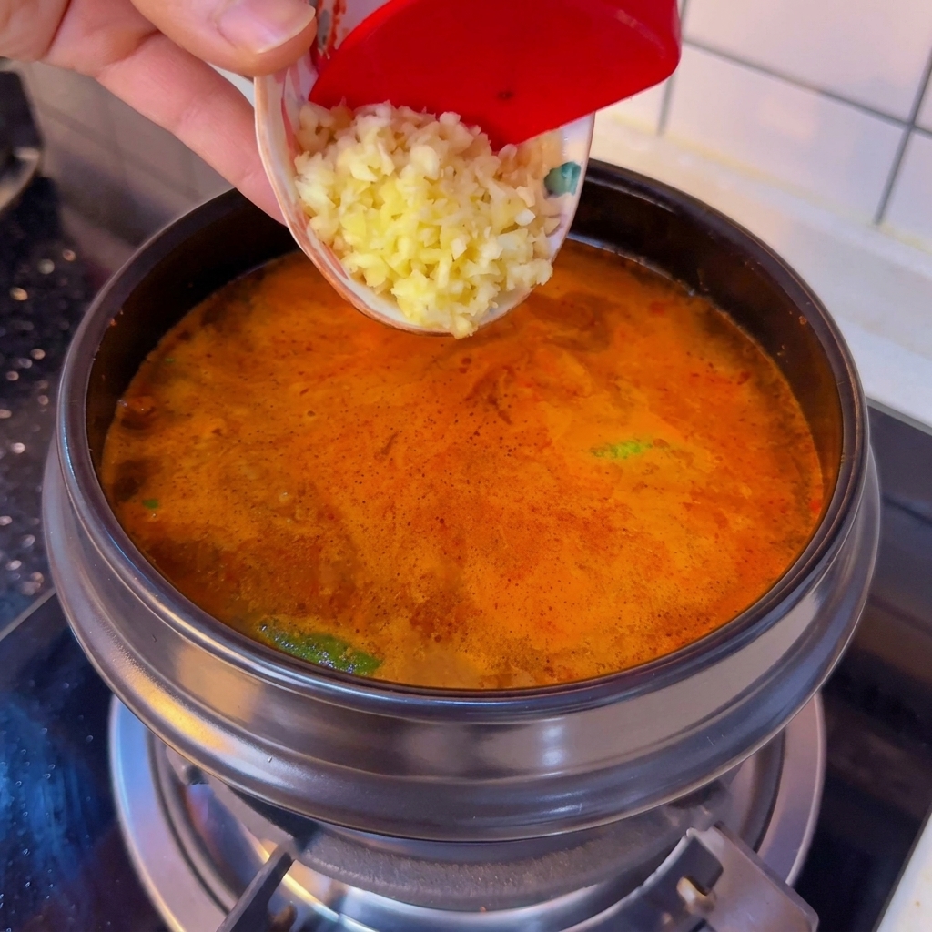 Ajo picado siendo añadido desde un pequeño bol a la cazuela.