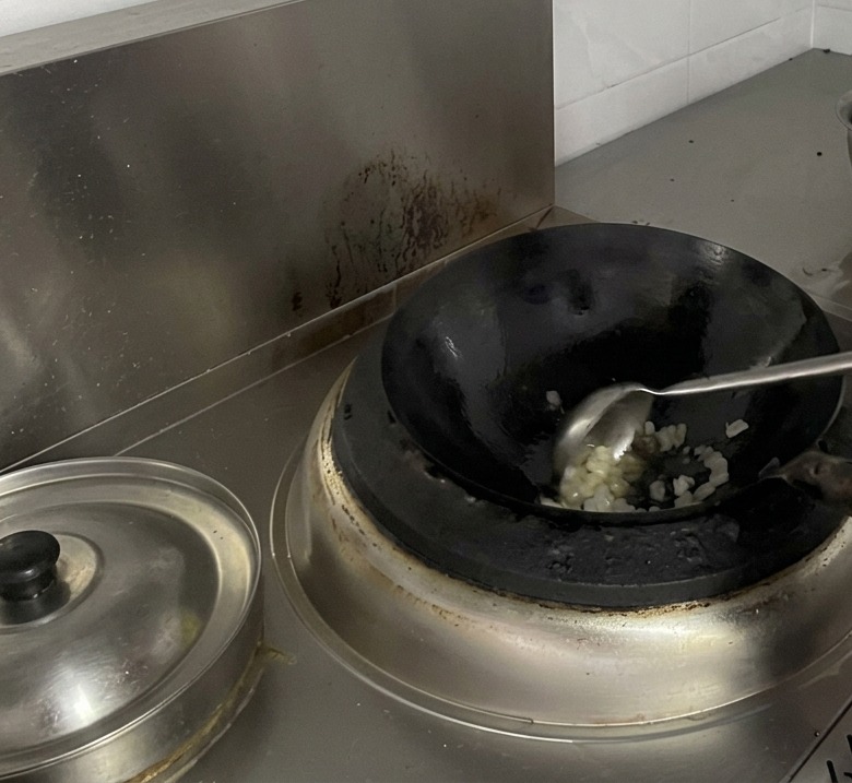 Cocinero removiendo azúcar derritiéndose en un wok.