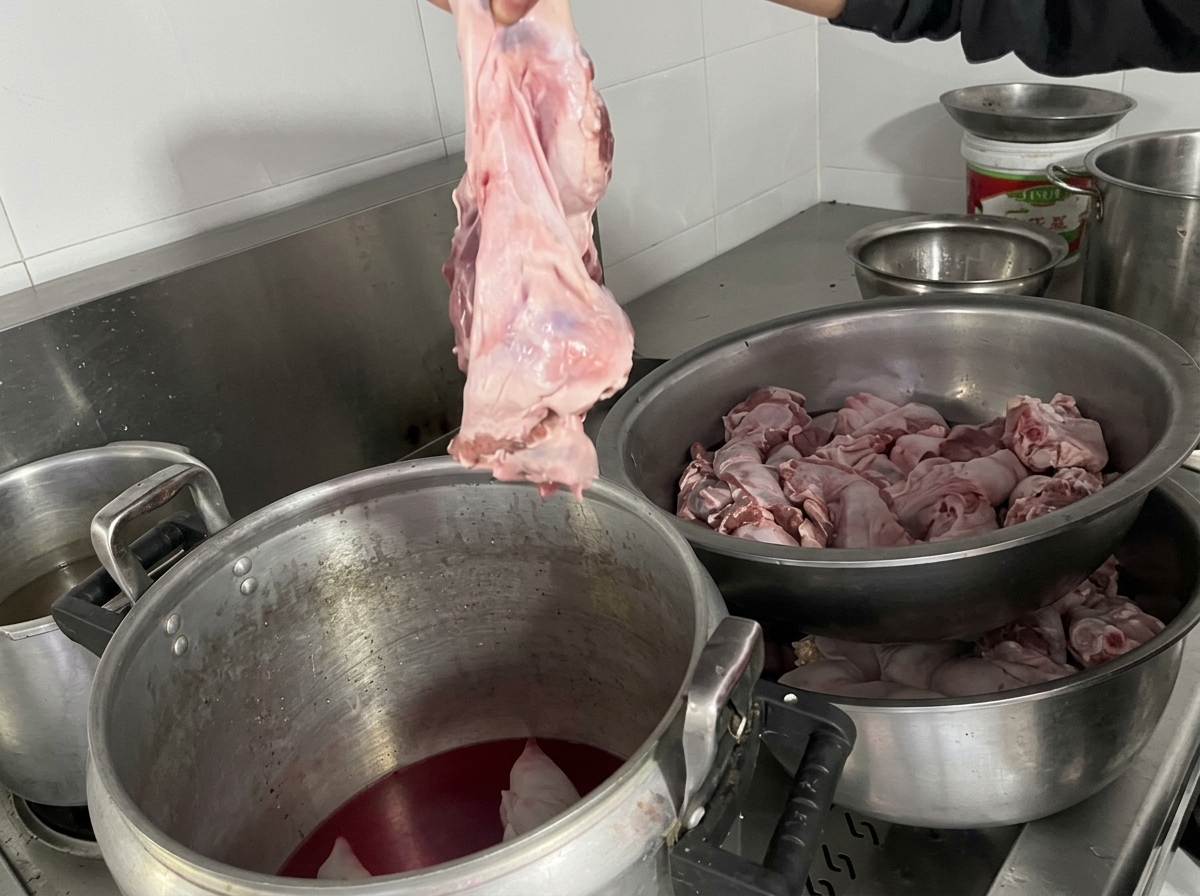 Mano introduciendo un trozo grande de carne de diafragma en la olla.