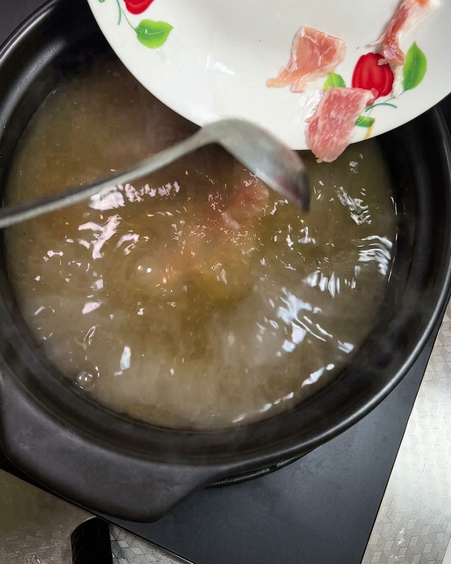 Trozos de zanahoria y patata siendo añadidos a la sopa.