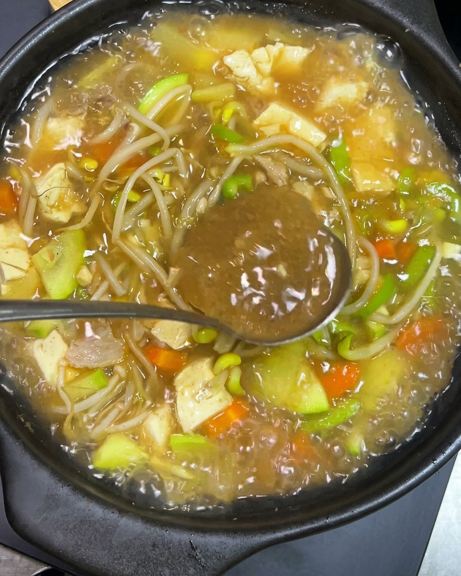 Pasta picante coreana siendo disuelta en el caldo hirviendo.