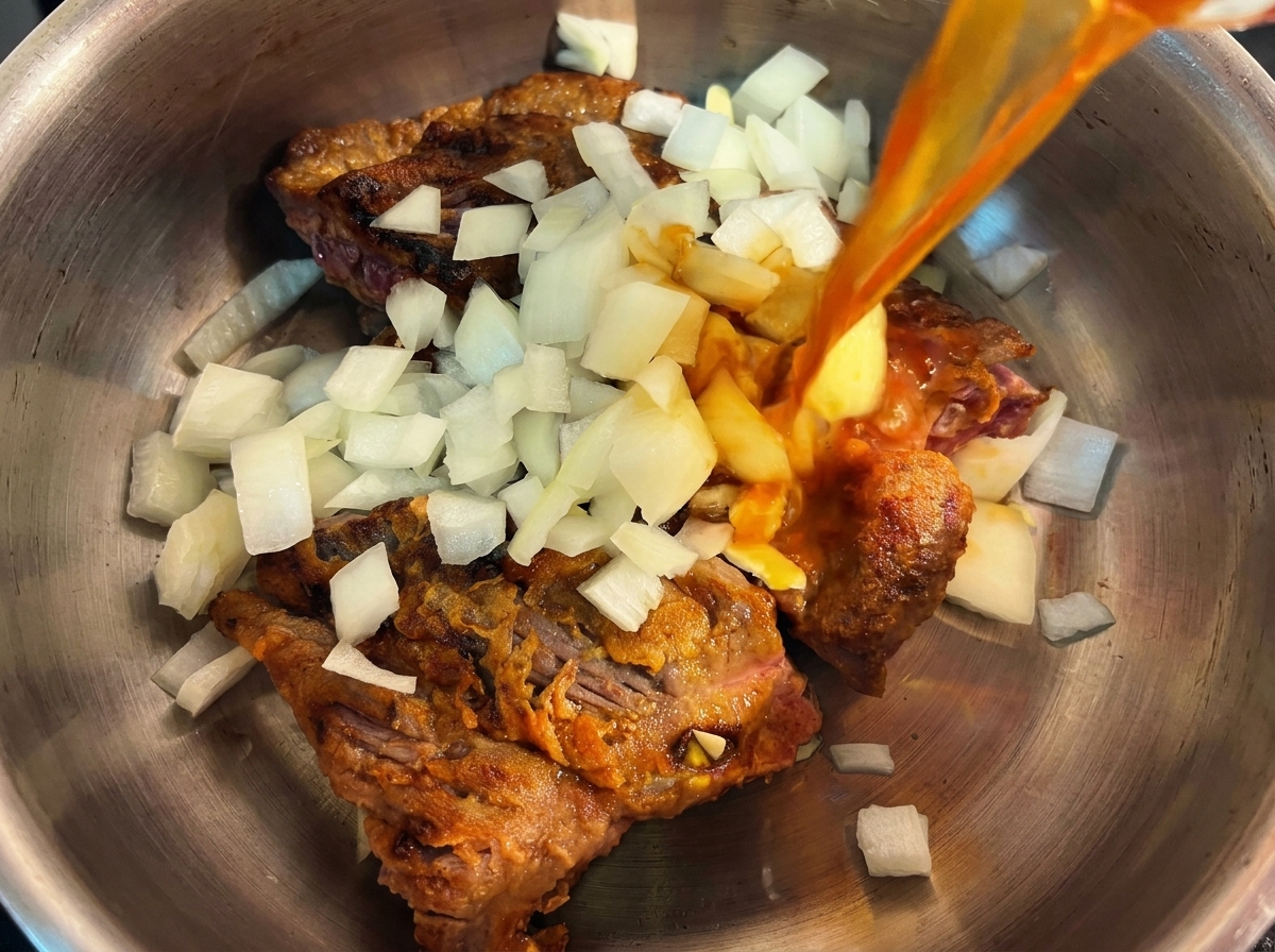 Una olla a presión que contiene carne dorada y cebolla picada, sobre la que se vierte un caldo sabroso.