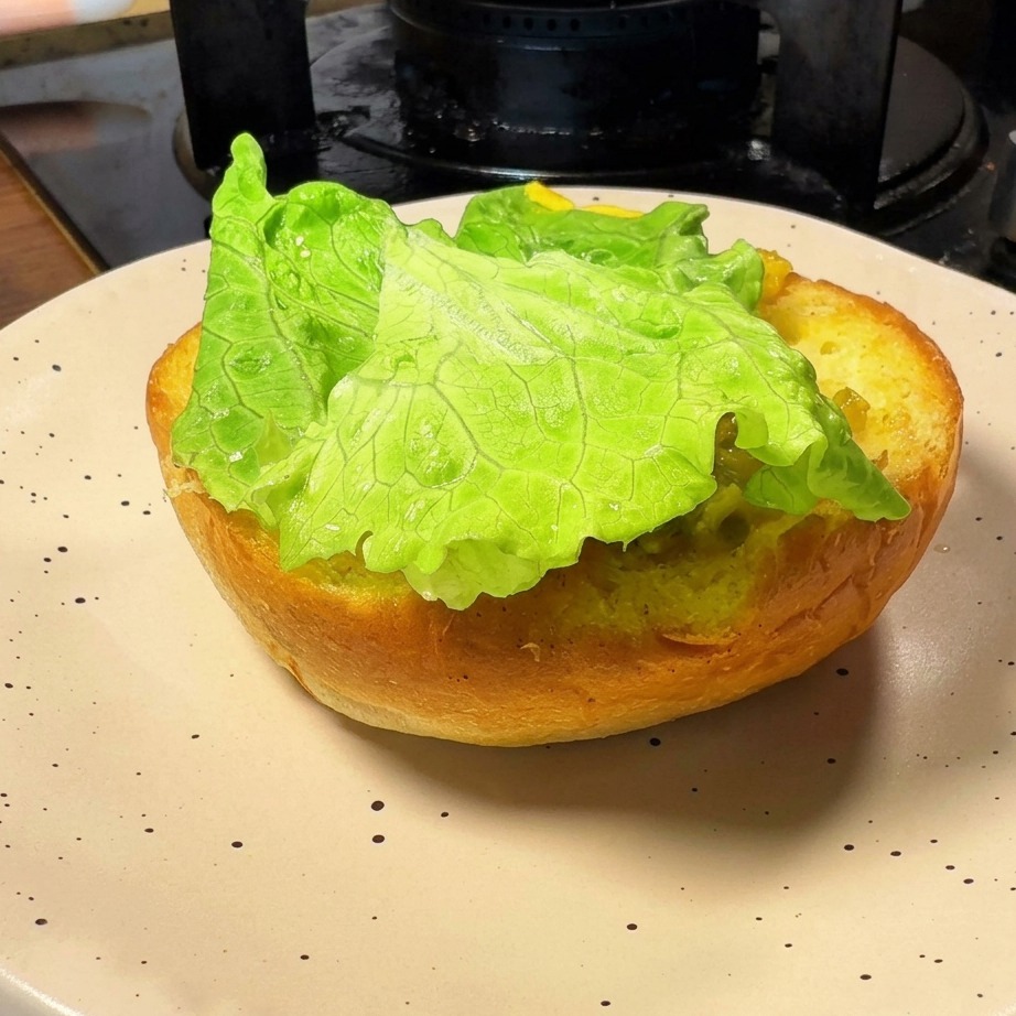 La base tostada de un pan de hamburguesa cubierta con una hoja de lechuga verde y fresca.