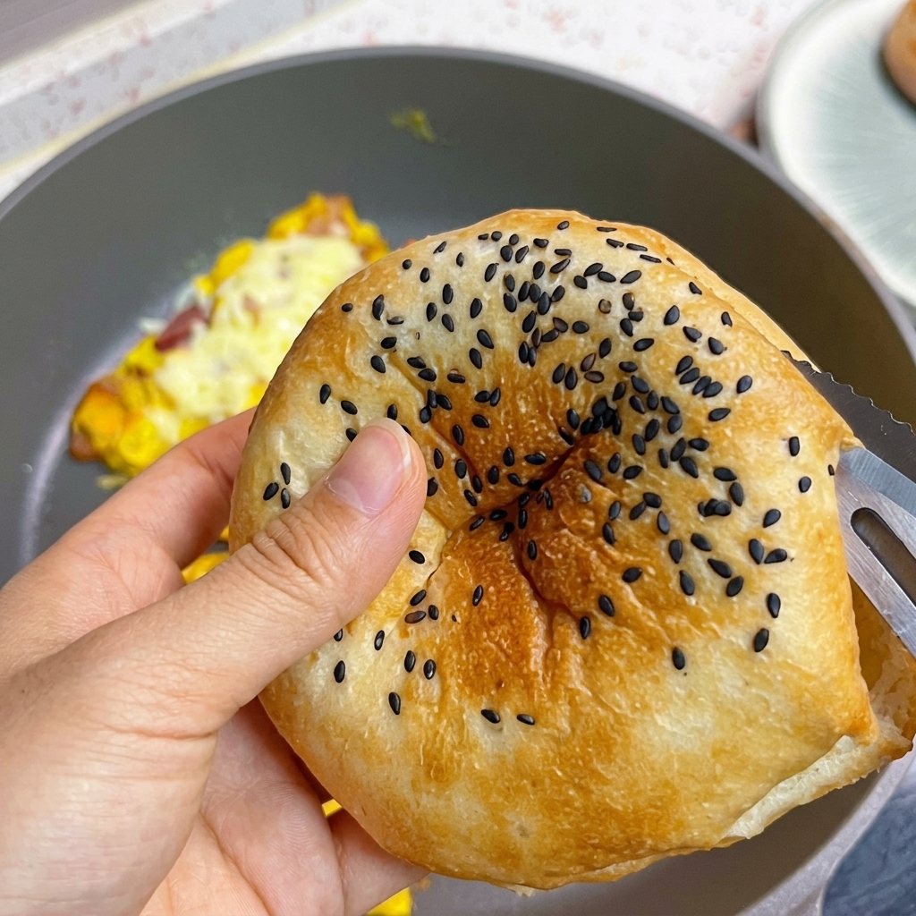Un pan de hamburguesa tostado con semillas de sésamo negro siendo abierto.