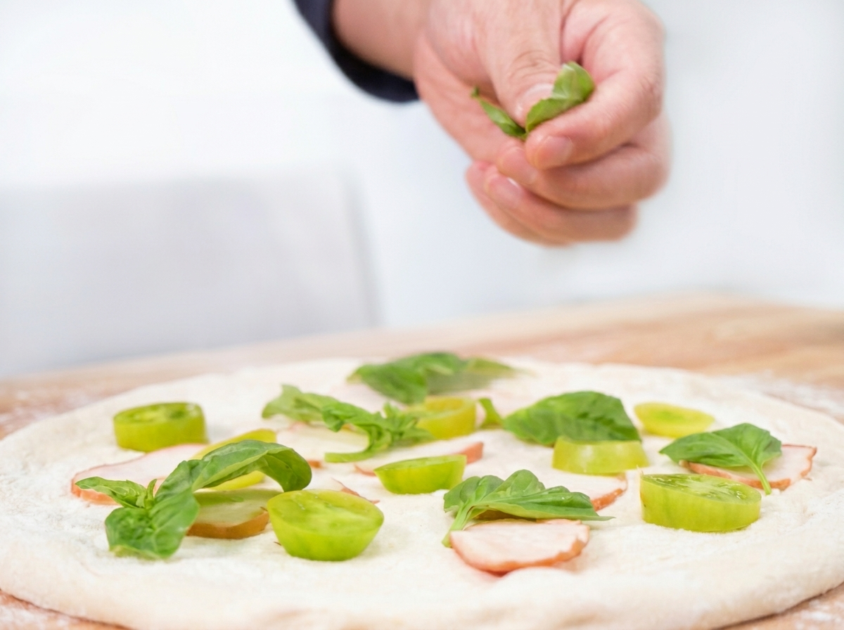 Hojas de albahaca fresca esparcidas sobre los ingredientes de la pizza.