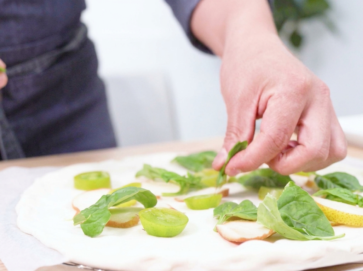 Mozzarella de búfala fresca desgarrada a mano sobre la pizza preparada.