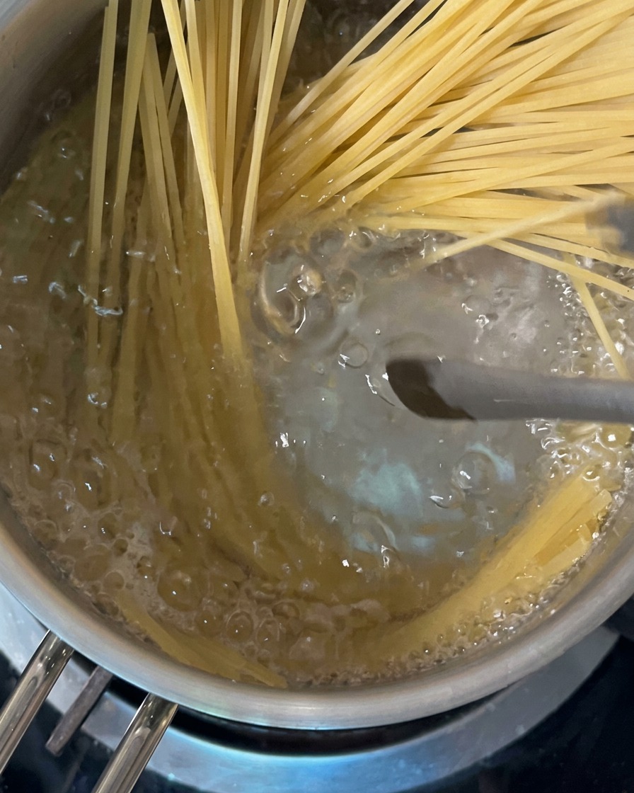 Espaguetis secos siendo introducidos en una olla de agua hirviendo.