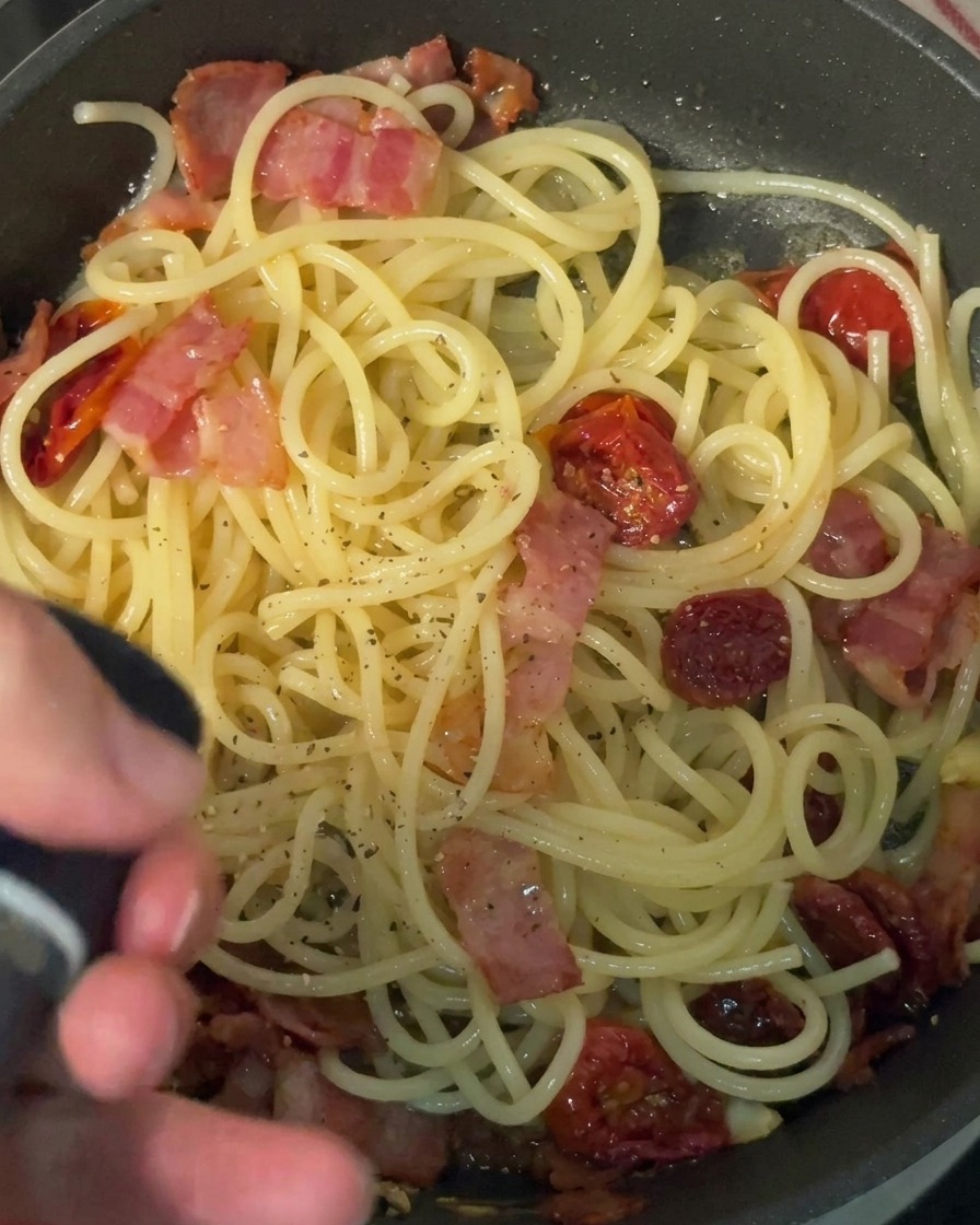 Moliendo pimienta negra fresca sobre una sartén de pasta.