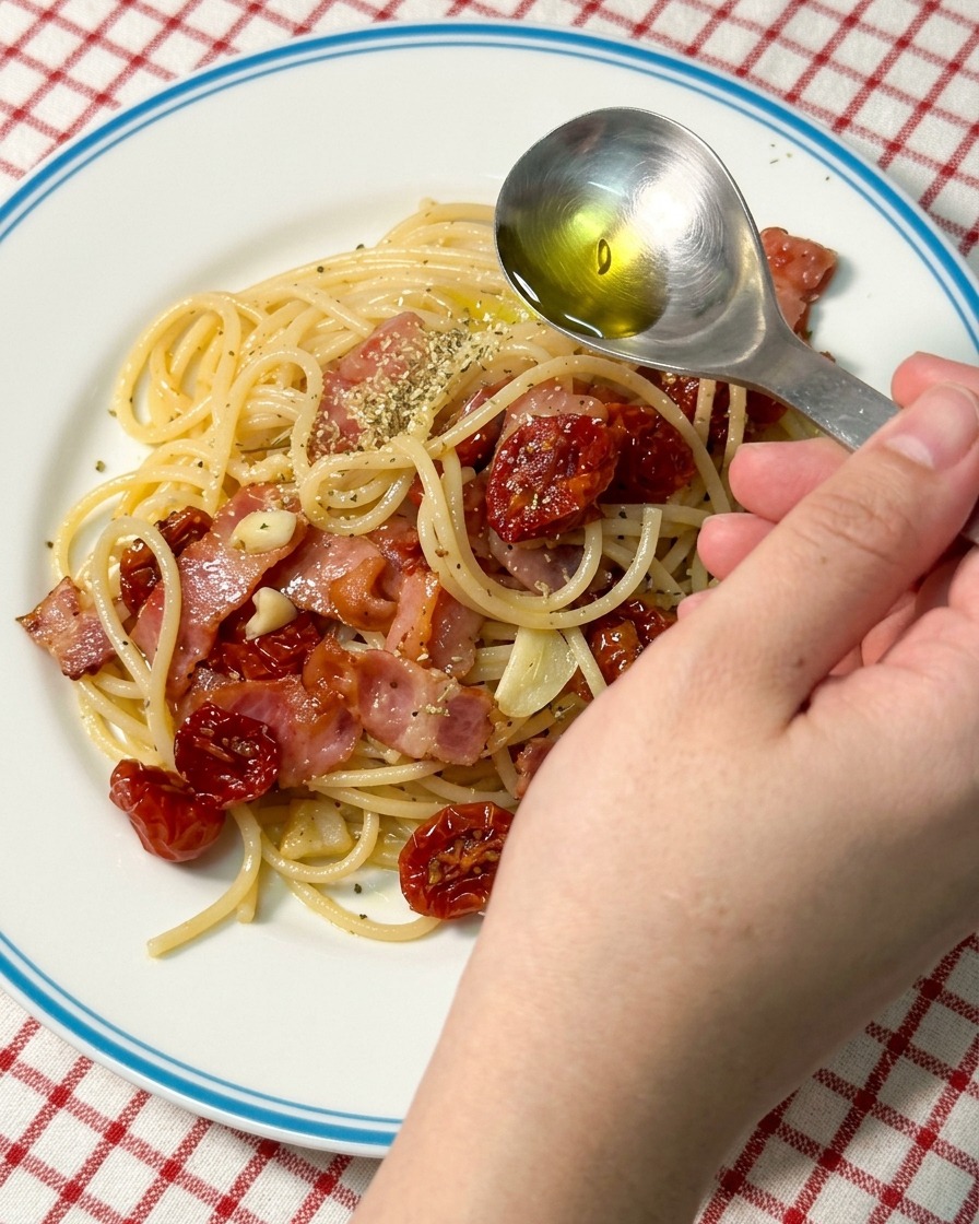 Una cuchara vertiendo aceite de oliva sobre un plato de pasta.