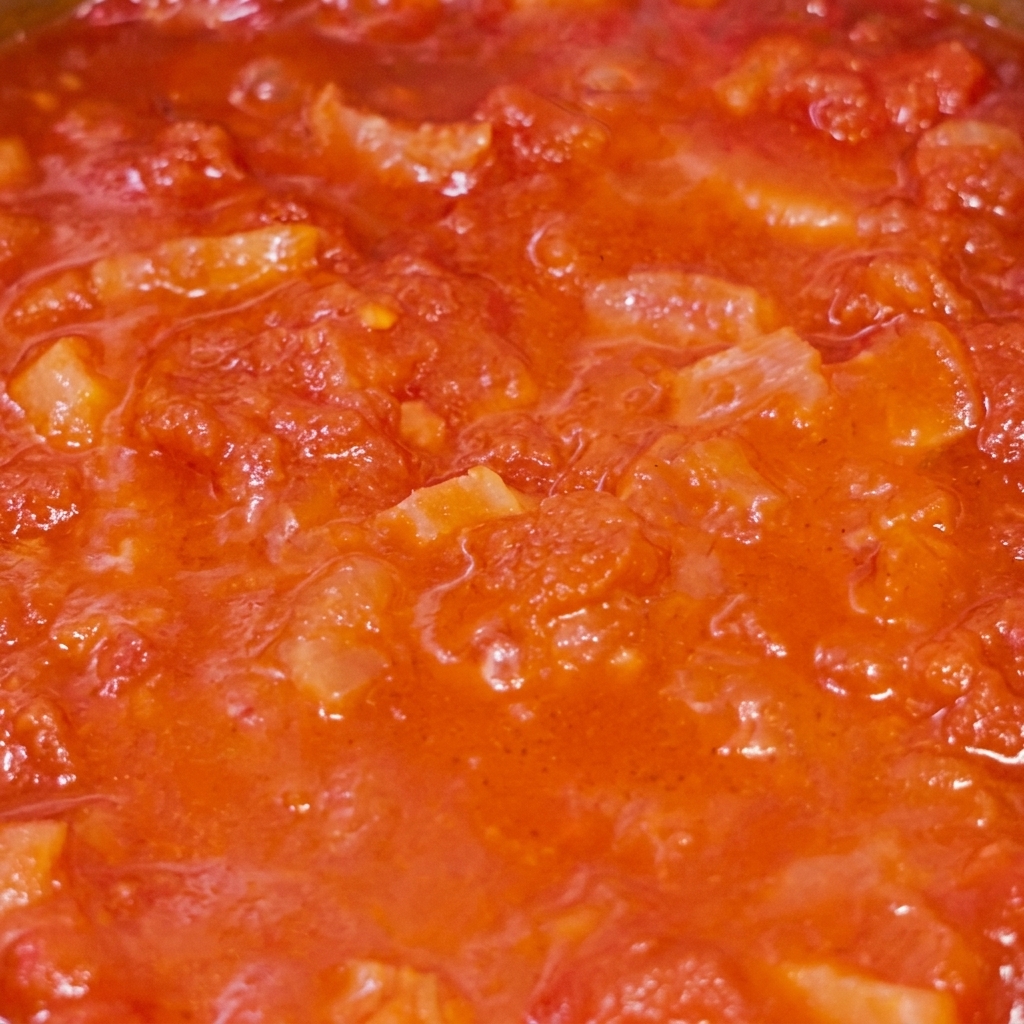 Primer plano de la salsa de tomate y tocino cociéndose a fuego lento.