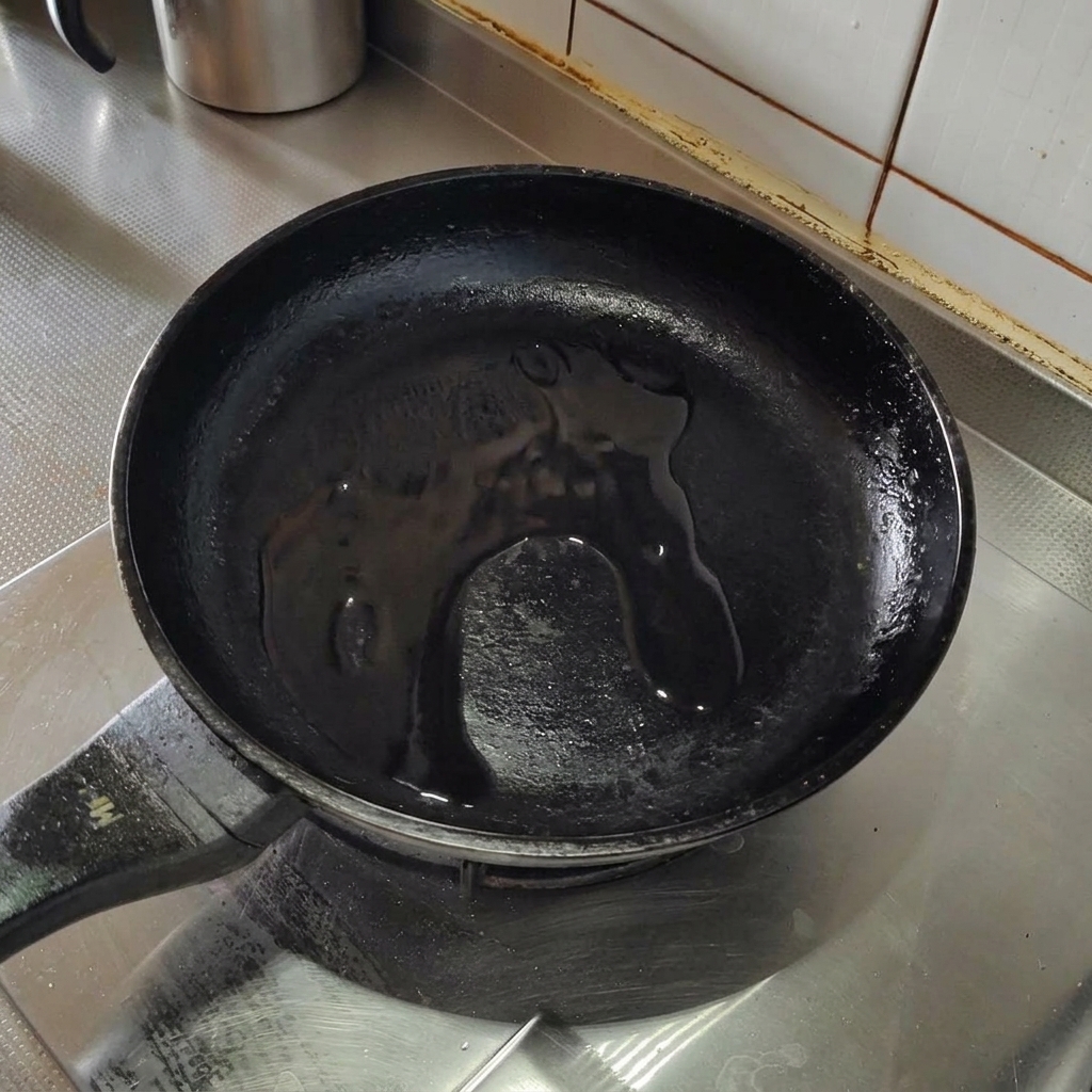 Trozos de tocino crujiente friéndose en aceite de oliva en una sartén de acero inoxidable.