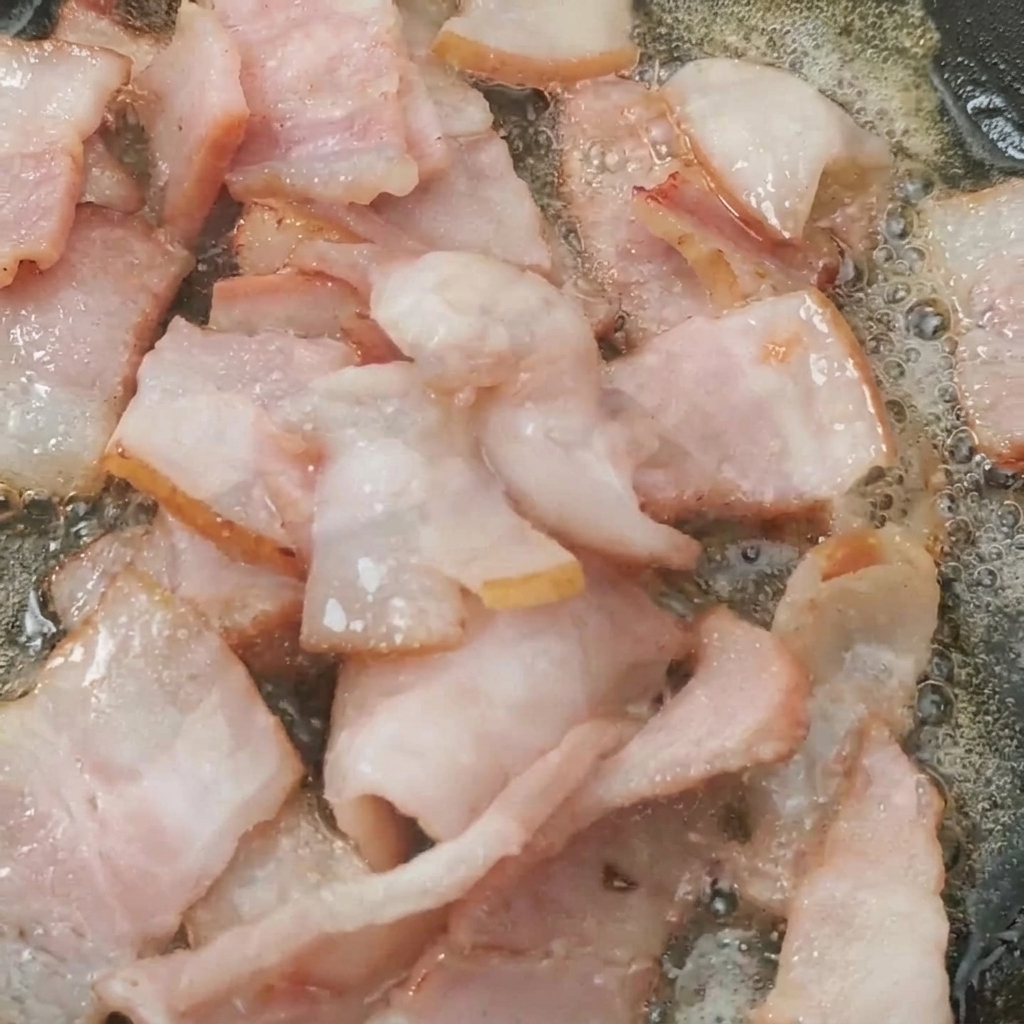 Tomates cherry en la sartén cocinándose junto al bacon crujiente.